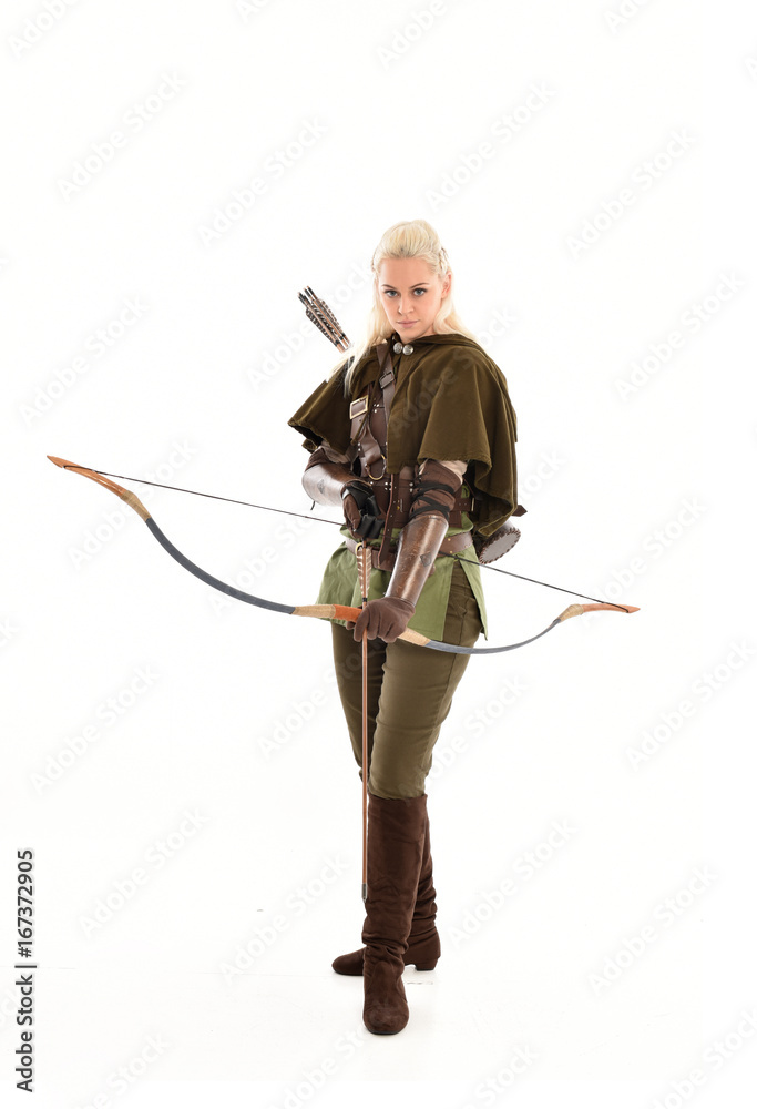 full length portrait of a blonde girl wearing green and brown medieval costume, holding a bow and arrow. isolated on white background. full length portrait of a blonde girl wearing green and brown medieval costume, holding a bow and arrow. isolated on white background.