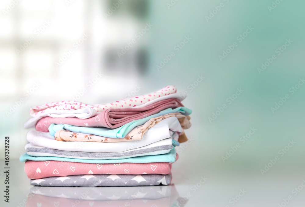 Pastel baby clothes stack pile empty space background. Stock Photo