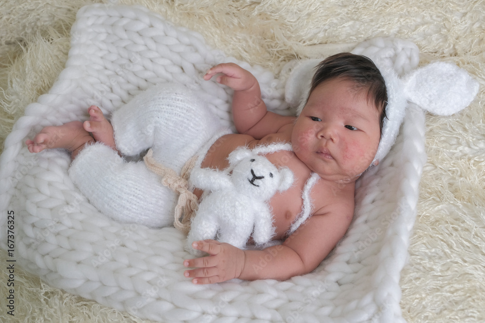 Fototapeta premium cute asian boy newborn portrait with white doll one month lie down on white background fur .