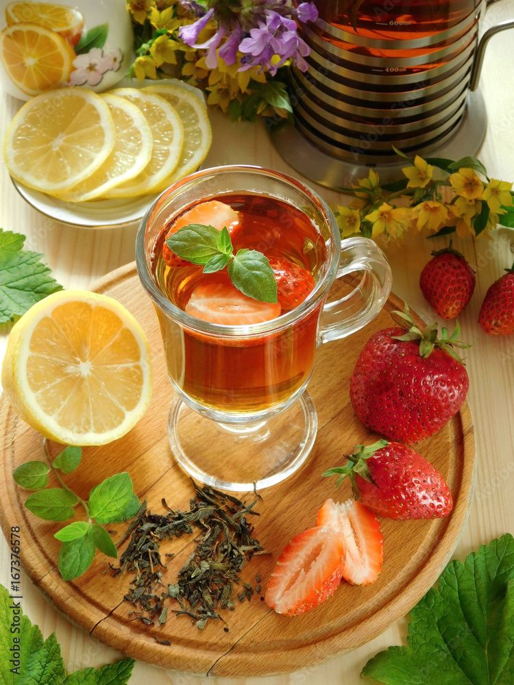 Spicy tea with strawberries illuminated by the sun rays on a wooden background Spicy tea with strawberries illuminated by the sun rays on a wooden background
