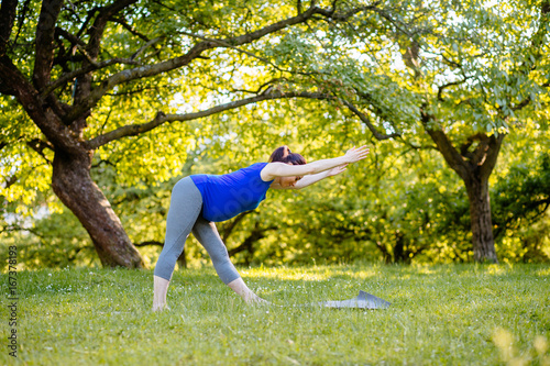 Young sporty female doing a different exercises for pregnant women on yoga mat outdoor. Fitness woman breathing fresh air, calm and dreaming, in green summer park.