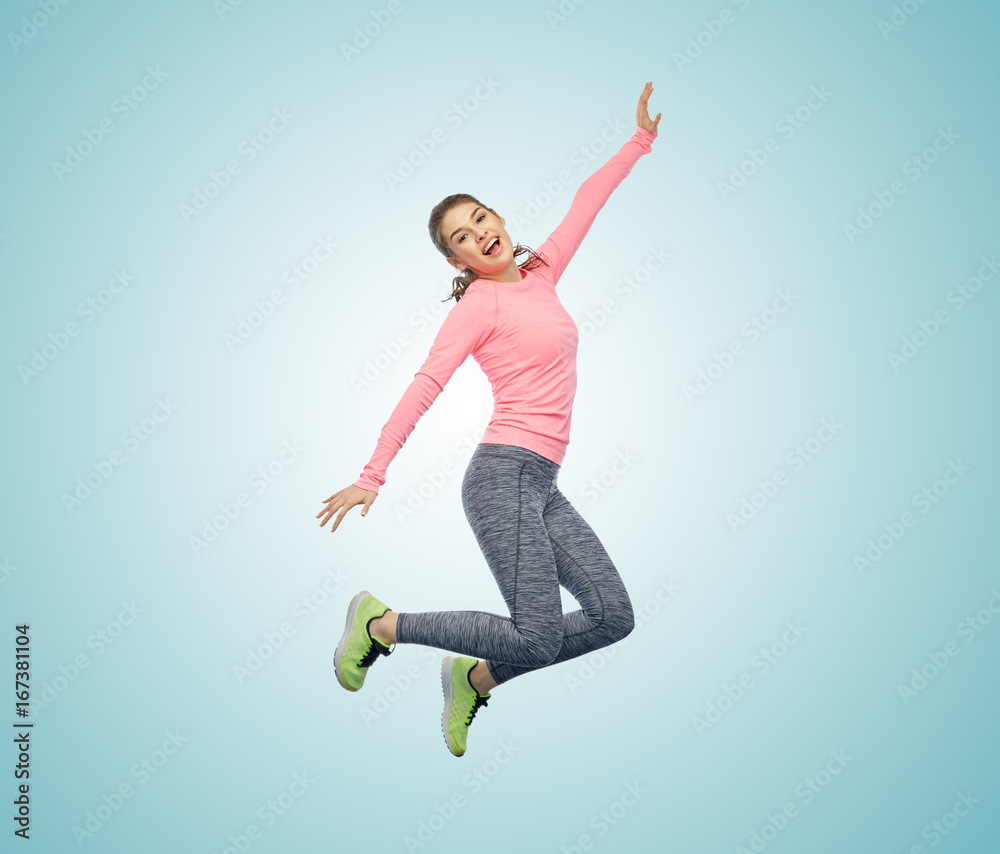 Obraz premium happy smiling sporty young woman jumping in air
