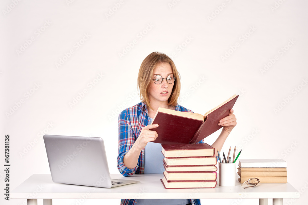 Beautiful teenage schoolgirl sitting at desk with stack of books on it Beautiful teenage schoolgirl sitting at desk with stack of books on it