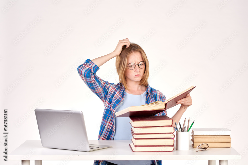 Beautiful teenage schoolgirl sitting at desk with stack of books on it Beautiful teenage schoolgirl sitting at desk with stack of books on it