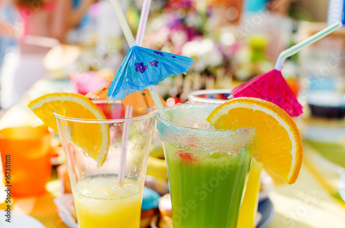 Summer non-alcoholic cocktails with umbrellas. Green and orange fresh drink.