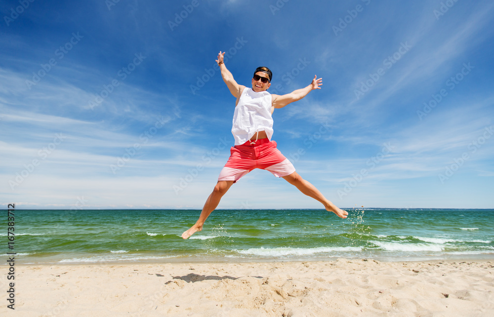 smiling young man jumping on summer beach smiling young man jumping on summer beach