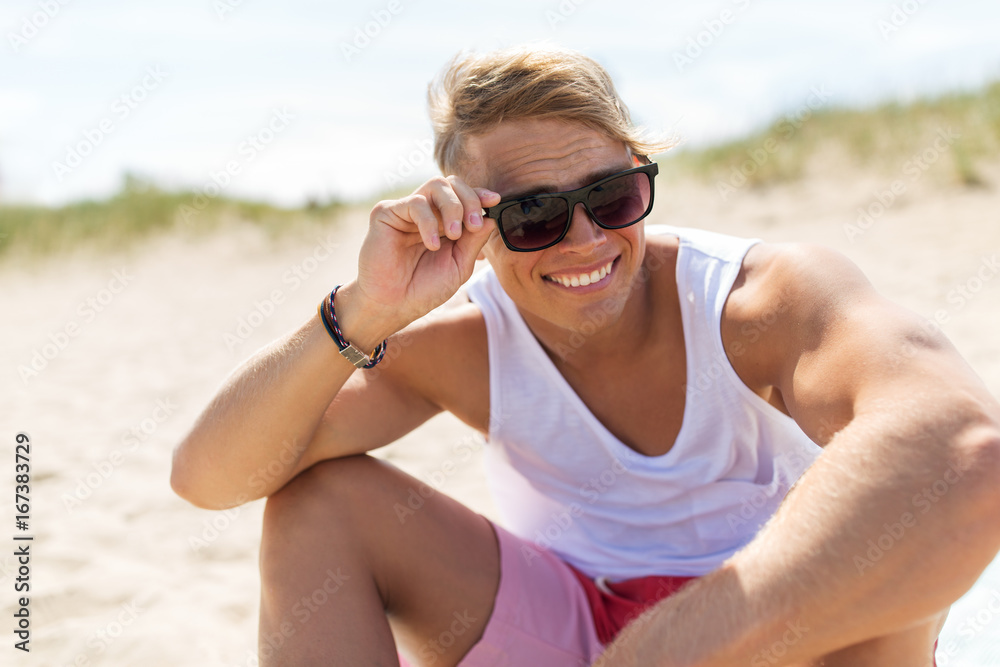 smiling young man in sunglasses on summer beach smiling young man in sunglasses on summer beach