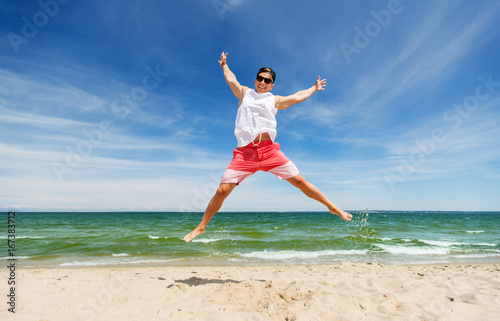 smiling young man jumping on summer beach