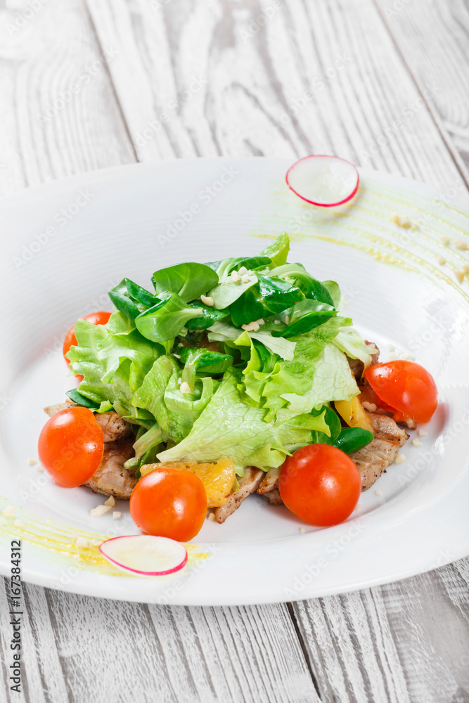 Fresh salad with chicken breast, baby spinach, lettuce, cherry tomatoes and cheese on wooden background close up