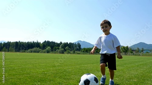 Tracking camera of a little 3 years old boy scoring a goal in a football field