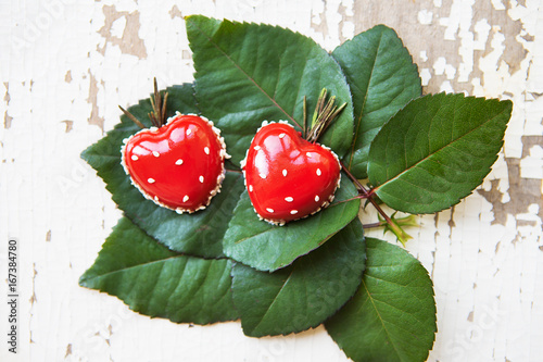 Beautiful and tasty dessert in the form of heart lies on green leaves on an old wooden background. photo