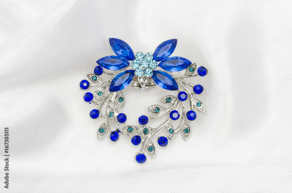 Silver flower brooch with blue diamonds on silk fabric Silver flower brooch with blue diamonds on silk fabric