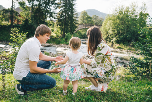 happy family play with daughter near the river in mountains photo