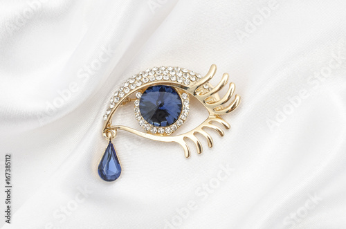 Gold brooch eye with diamonds with large sapphire on a silk fabric