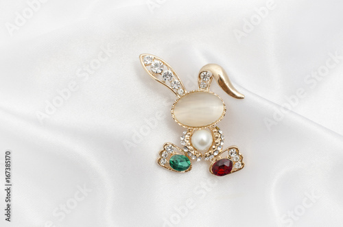 Golden brooch bunny with diamonds and moonstone on silk fabric