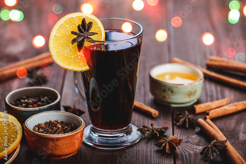 Christmas mulled wine with cinnamon, anise stars, honey and orange slices on wooden background with Holiday light