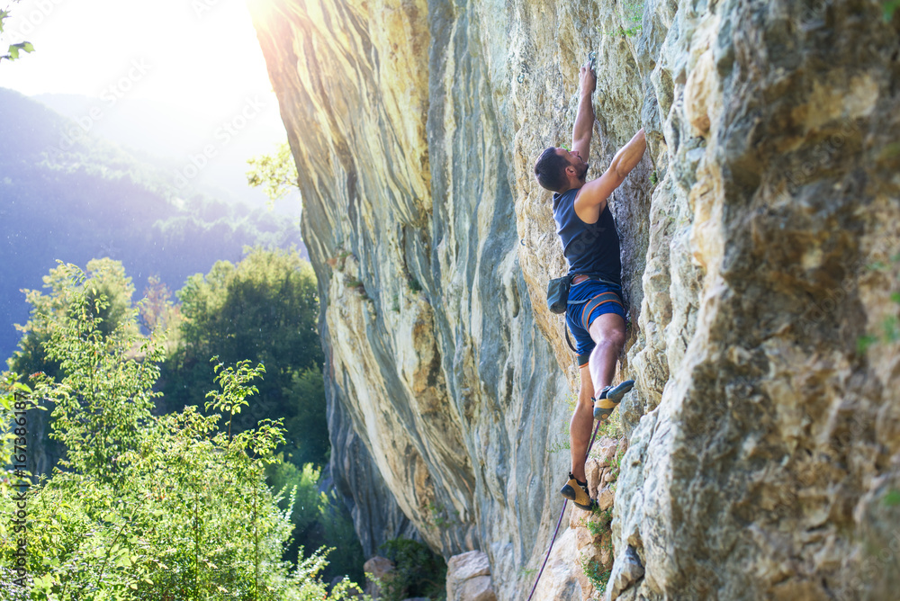 Rock climber with hand in chalk bag hanging on boulder Rock climber with hand in chalk bag hanging on boulder