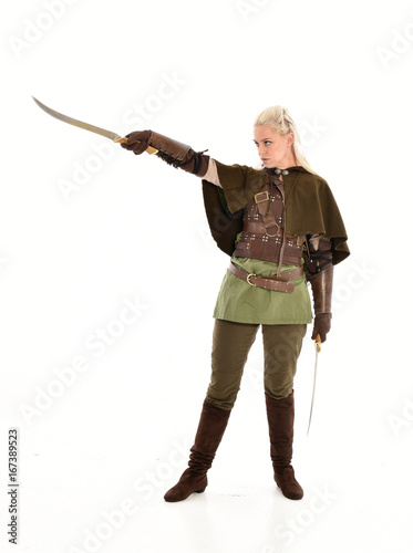 full length portrait of a blonde girl wearing green and brown medieval costume, holding a bow and arrow. isolated on white background. photo