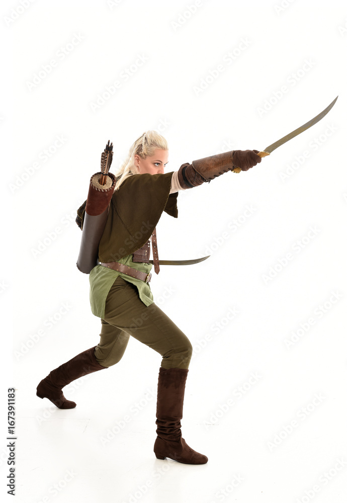 full length portrait of a blonde girl wearing green and brown medieval costume, holding a bow and arrow. isolated on white background. full length portrait of a blonde girl wearing green and brown medieval costume, holding a bow and arrow. isolated on white background.