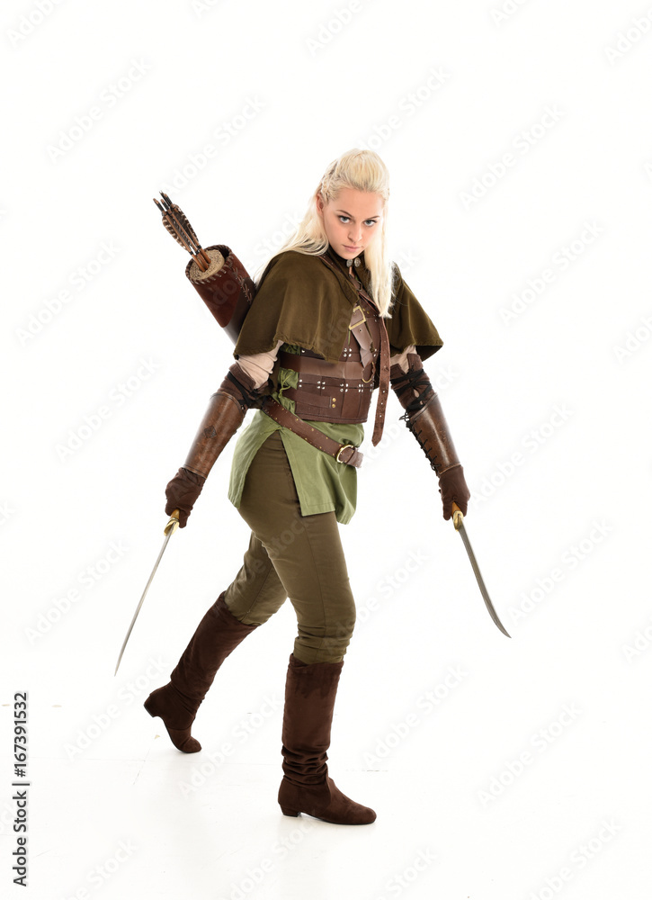 full length portrait of a blonde girl wearing green and brown medieval costume, holding a bow and arrow. isolated on white background. full length portrait of a blonde girl wearing green and brown medieval costume, holding a bow and arrow. isolated on white background.
