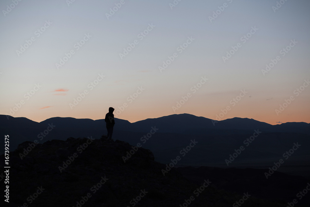 Man silhouette stay on sharp rock peak. Satisfy hiker enjoy view. Tall man on rocky cliff watching down to landscape.