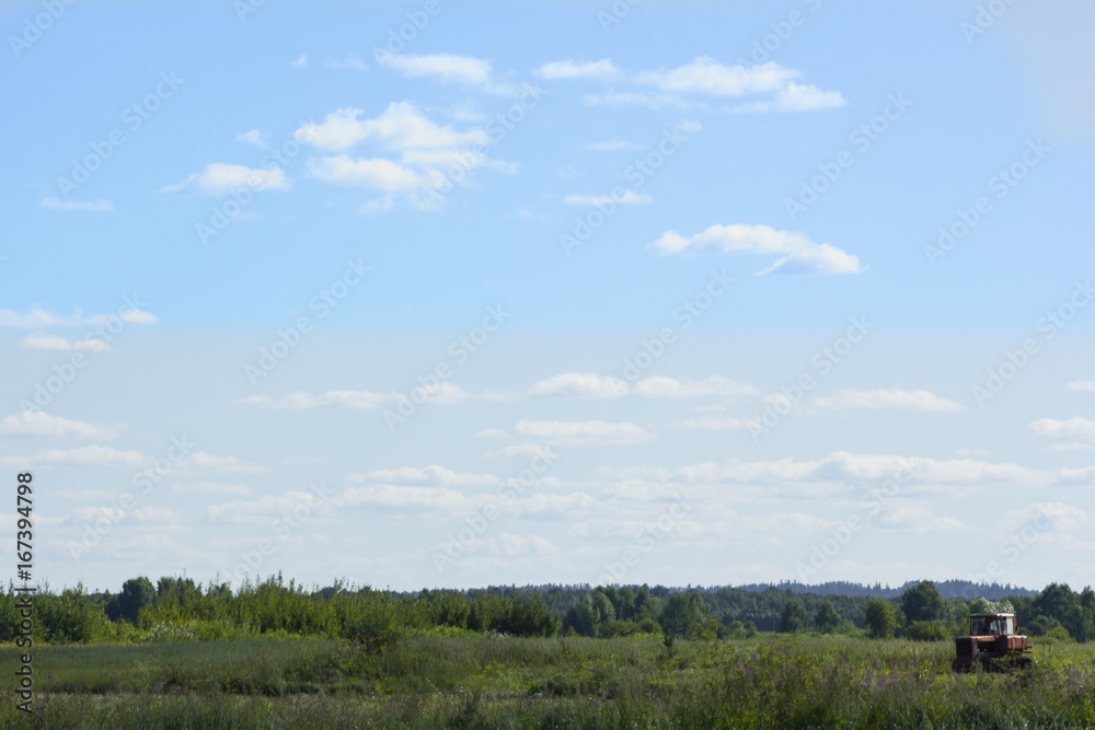 Landscape of a green field against a blue sky With an old tractor Landscape of a green field against a blue sky With an old tractor