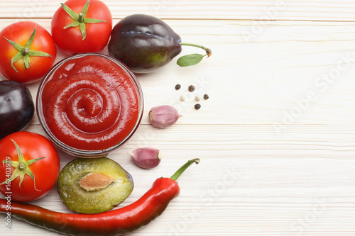 raw plum, tomato and ketchup on wooden table. top view