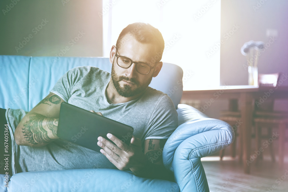 man lying on sofa with digital tablet pc at home