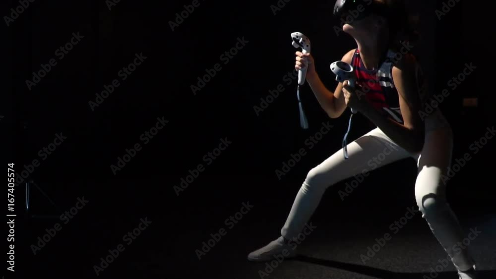 A girl in virtual reality glasses plays and beats someone with a joystick A girl in virtual reality glasses plays and beats someone with a joystick