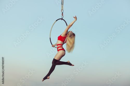 Female acrobat while presenting the show in the air on the hoop. © Petro
