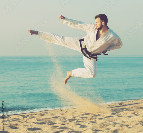 Guy practising karate at seaside