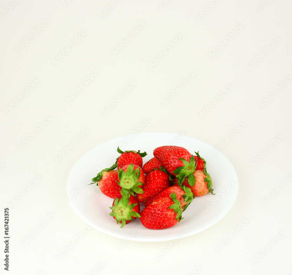 Fresh strawberries with leaf in a white plate on white background