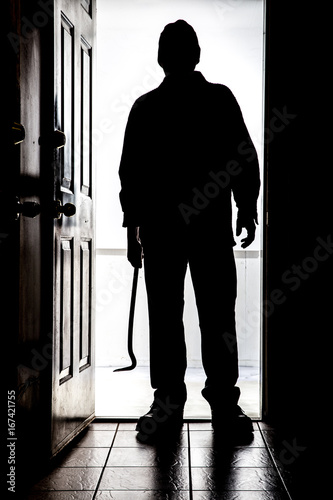 Photo Intruder at door, in silhouette with crowbar.