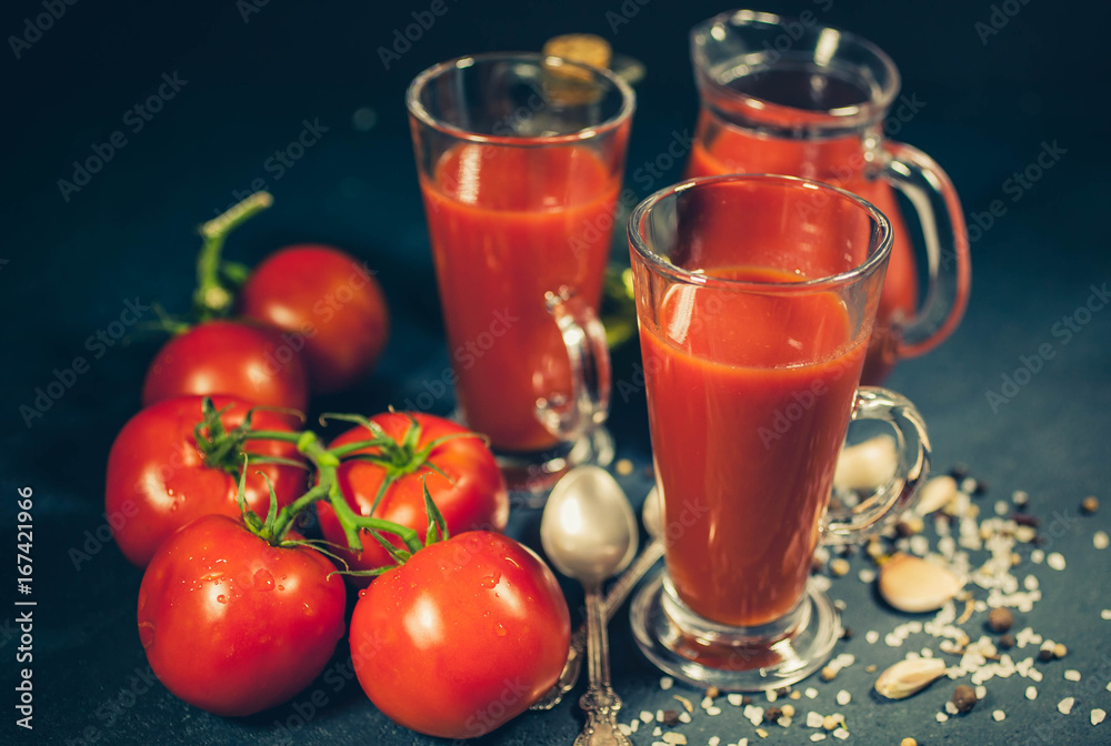 Red tomatoes, juice and spices on dark background. Tomato juice. Selective focus. Low-key lighting Red tomatoes, juice and spices on dark background. Tomato juice. Selective focus. Low-key lighting
