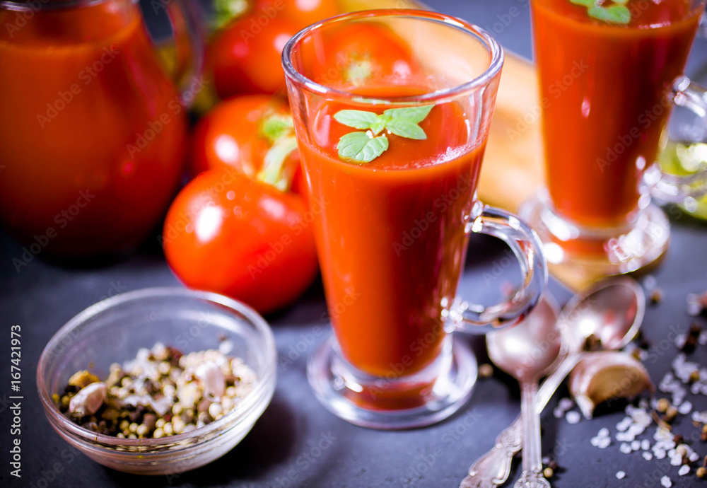 Red tomatoes, juice and spices on dark background. Tomato juice. Close up. Selective focus. Low-key lighting Red tomatoes, juice and spices on dark background. Tomato juice. Close up. Selective focus. Low-key lighting