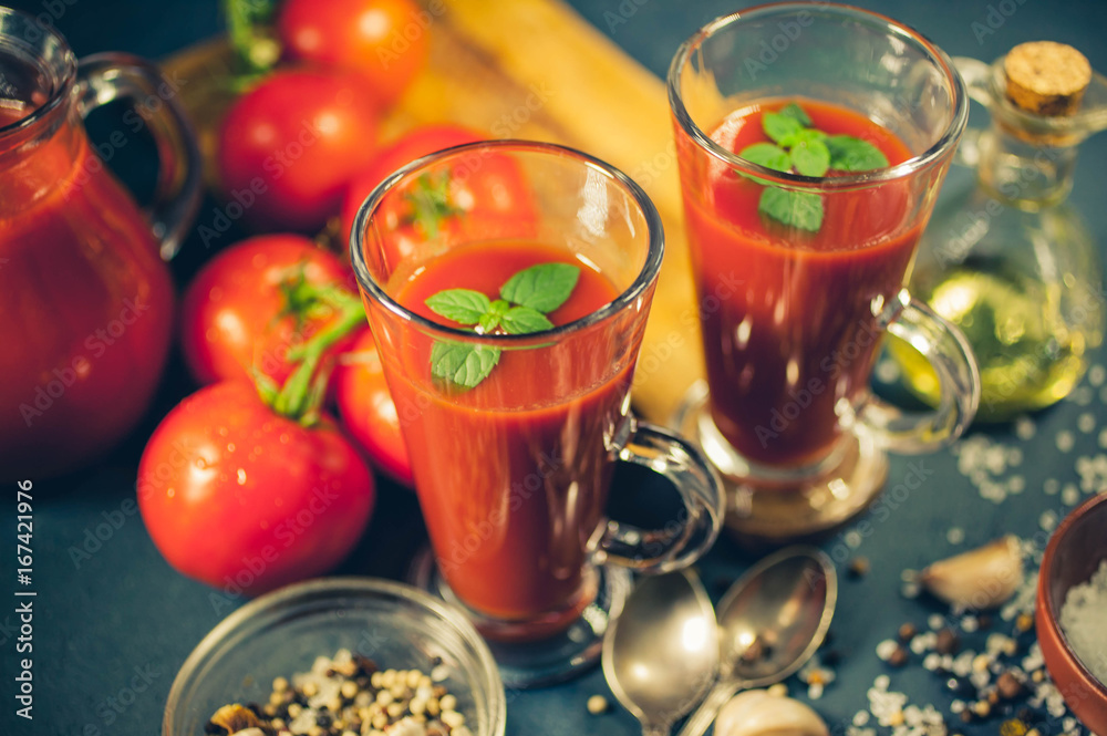 Red tomatoes, juice and spices on dark background. Tomato juice. Close up. Selective focus. Low-key lighting Red tomatoes, juice and spices on dark background. Tomato juice. Close up. Selective focus. Low-key lighting