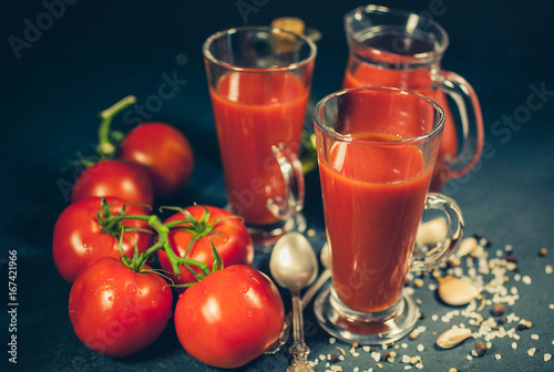 Red tomatoes, juice and spices on dark background. Tomato juice. Selective focus. Low-key lighting © yusev