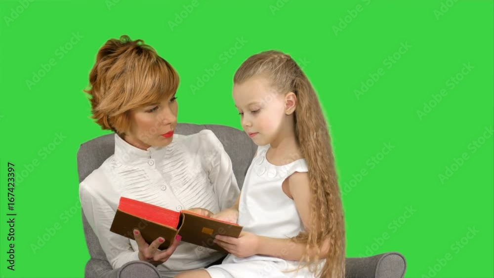 Mother and daughter reading book on the couch on a Green Screen, Chroma Key Mother and daughter reading book on the couch on a Green Screen, Chroma Key