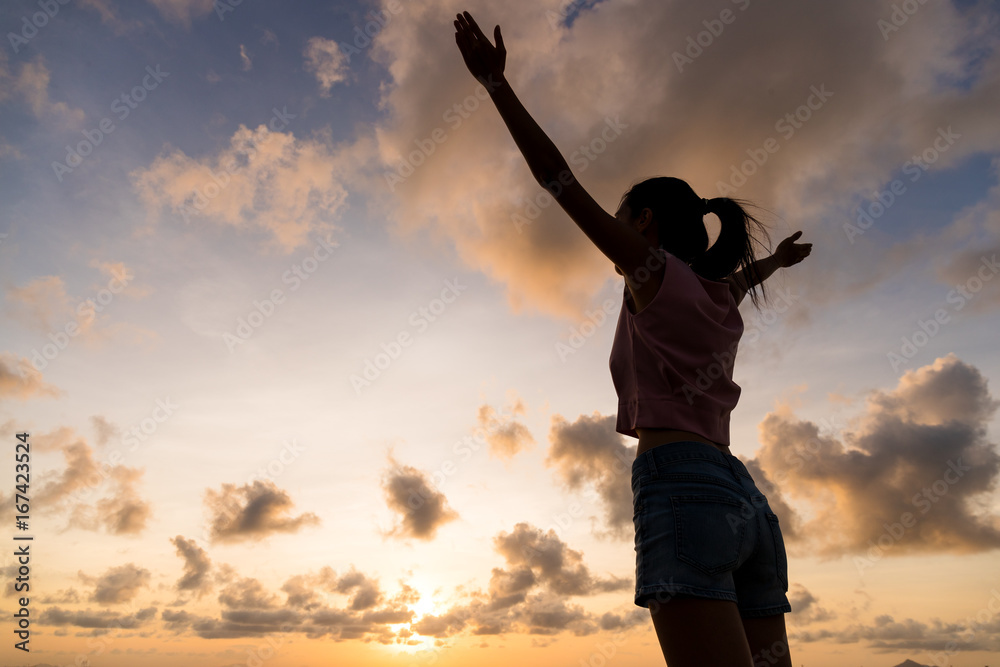 Silhouette woman hands up against sunset time