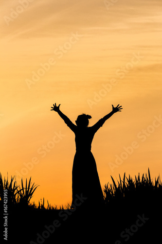 Silhouette of strong confidence woman open arms under the sunrise