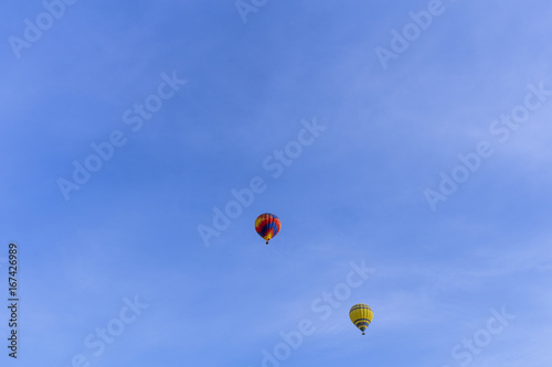 Two balloons flying over a blue sky