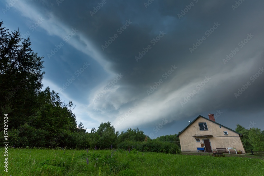 Scarry dark storm clouds over forest and house