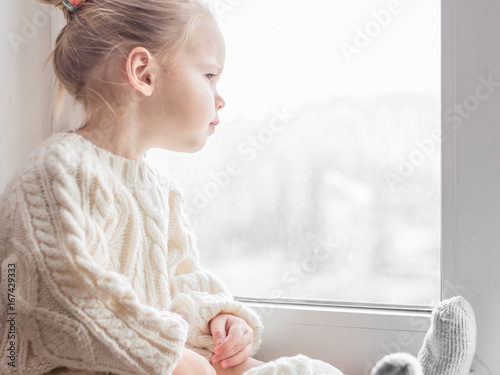 A little girl in the white knitted sweater