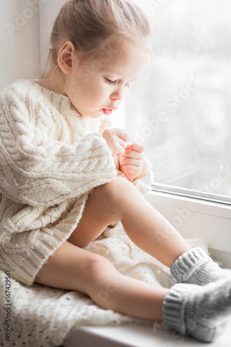 A little girl in the white knitted sweater