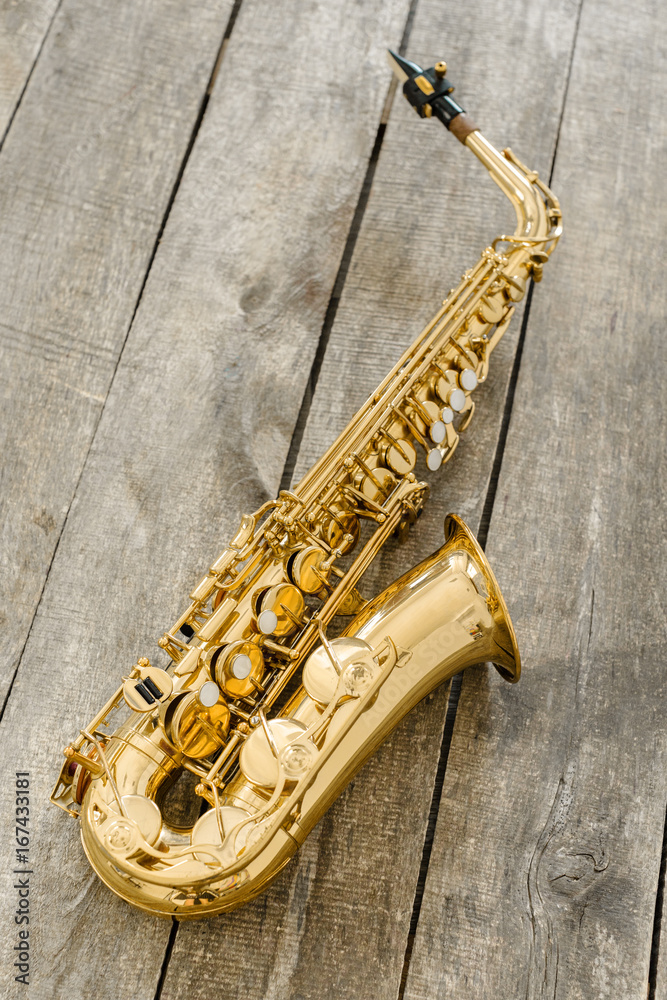 Naklejka premium Beautiful golden saxophone on wooden background