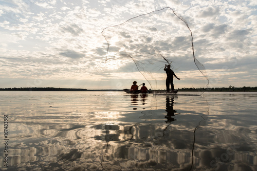 Silhouette of Fishermen throwing net fishing in sunset time at Wanon Niwat district Sakon Nakhon Northeast Thailand.