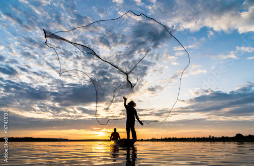 Silhouette of Fishermen throwing net fishing in sunset time at Wanon Niwat district Sakon Nakhon Northeast Thailand. photo