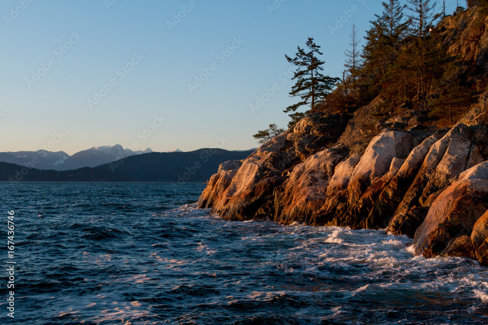 Ocean waves hitting rocks on coast while sunset