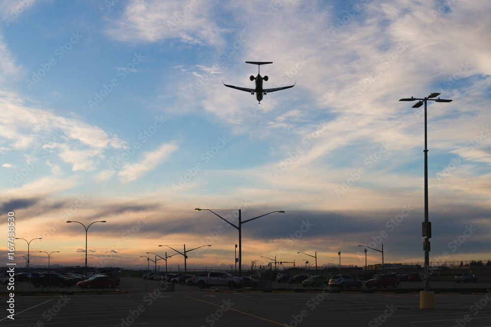 Plane flying low over parking lot while sunset