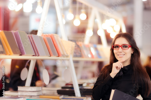 Smiling Girl Holding a Book in front of a Bookshelf photo